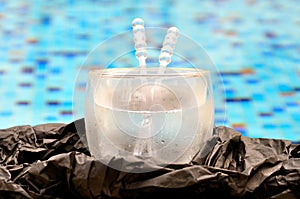 Close up view of an iced drink against a backdrop of a pool with blue and gold mosaic tiles