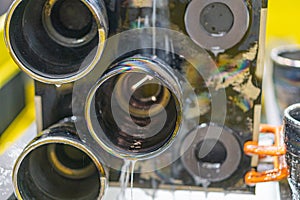 Close-up view of an industrial setting with metallic conduits, a black connector, and a yellowish background photo