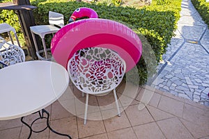 Close up view of inflatable pink flamingo swimming ring on chair of outdoor cafÃ©.