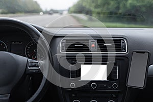 Close-up view inside car of dashboard with empty mockup on screen, and smartphone. GPS navigation system concept.