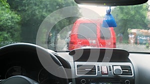 Close up view from inside of rain water drops falling on car windshield glass.