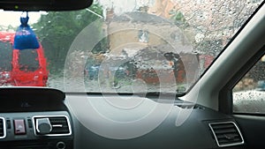 Close up view from inside of rain water drops falling on car windshield glass.