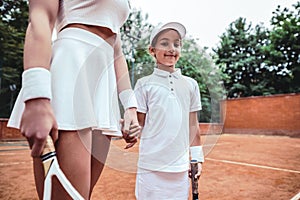 Close up view of Instructor or coach teaching child how to play tennis on a court