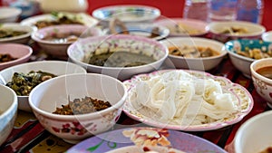 A close-up view of khanom jeen, curry, fried eggs, stir-fries and many other dishes packed in bowls