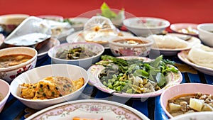 A close-up view of khanom jeen, curry, fried eggs, stir-fries and many other dishes packed in bowls