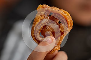 close up view of kid hand holding a piece of Chebakia a Moroccan pastry - Moroccan cookie famously associated with Ramadan and