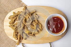 Close up view of kripik usus ayam and red chili sauces on wooden cutting board