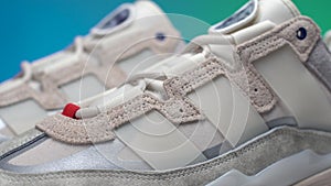 close up view on lace cage of suede crema adidas sneaker niteball rotating on isolated green and blue background