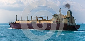 A close up view of a large Liquid Natural Gas tanker ship sailing northward in the Singapore Straits in Asia