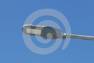 Close up view of LED street light with solar cell on clear blue sky background with clouds.