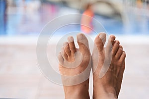 Close up view of legs and toes and swimming pool. relaxation alone concept
