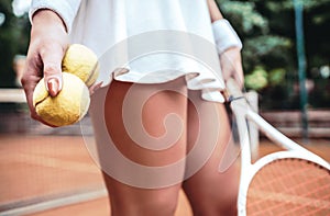 legs of young girl in a tennis court with ball and racket