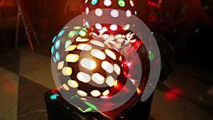 Close-up view of light ball. Colored disco projector rounding. Light show shining in the dark in night club.