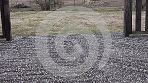 Close up view of light hail storm on wet wooden terrace covered by white round frozen hailstones. Countryside garden view with old