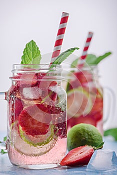 Close up view on lime and strawberry detox drink in glass mason jars on a blue background 4
