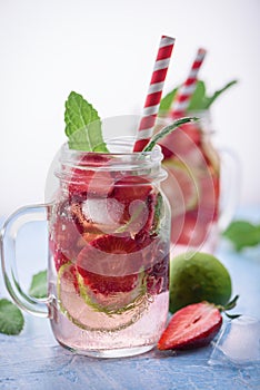 Close up view on lime and strawberry detox drink in glass mason jars on a blue background 7