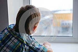 Close up view of little boy looking out of window