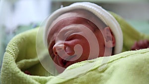 Close up view of a little newborn baby crying and moving.