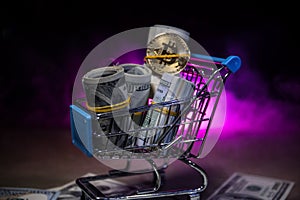 close up view of little shopping trolley full of coins isolated on brown.Gold coins in shopping online cart isolated on brown back