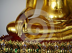 Close up view of the low hand golden buddha statue sitting meditation with copy space and sunlight