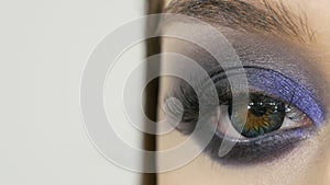 Close up view of makeup artist makes models smoky eyes with the help of special brush blue eyeshadow, eyes and eyelashes