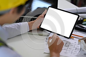 Male architect using digital tablet and working blueprint at office desk. Architecture design concept.