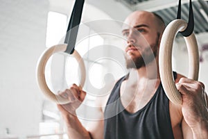 Close up view on male gymnast doing workout on gymnastics rings in cross gym