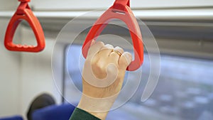 Close up view of male hand holding a looped handle in urban public transportation