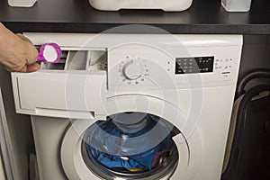 Close up view of male hand lay detergent into washing machine.