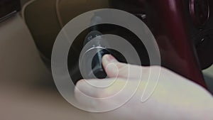 A close up view of male hand pressing the controlling buttons for electric seat adjustment inside a car. Interior door