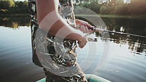 Close-up view of male hands holding the fishing rod with spinning reel. Young man catching the fish alone.