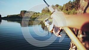 Close-up view of male hands holding the fishing rod. Young Fisher man twisting the rod with spinning reel.