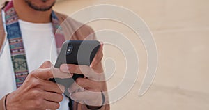 Close up view of male hands typing on mobilephone screen. Crop view of man using smartphone while walking at street