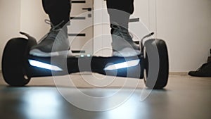 Close-up view of male legs stepping on electric hyroscooter in modern office space with white walls and moving away.