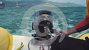 Close up view of a man controlling a motor inflatable boat in the sea.