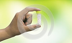 Close-up view of a man hand holding a bottle of homeopathic pills on a mix green yellow background