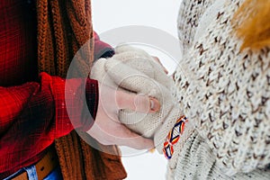 Close-up view of the man hands holding the woman hands in knitted gloves. Winter time.