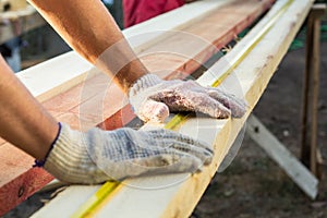 Close up view of a man hands measuring wooden plank with a tape line