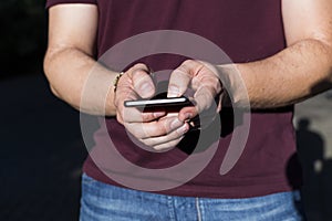 close up view of man hands typing on smart phone. Casual clothing. sunset. Outdoors. lifestyles.