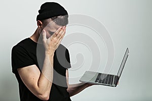 Close up view of man with laptop and facepalm.
