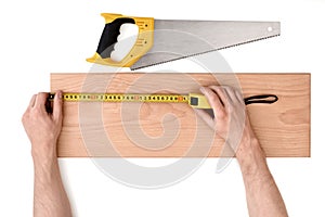 Close up view of a man's hands measuring wooden plank with tape line, isolated on white background