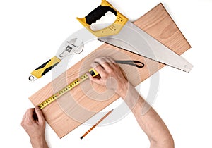 Close up view of a man's hands measuring wooden plank with tape line, on white background