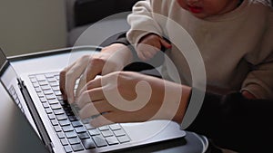 Close up view of man's hands typing on laptop while cute toddler boy disturbs him