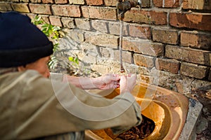 Close up view of man squating to wash hands.