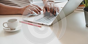 Close-up view of man typing on laptop computer in cozy workplace