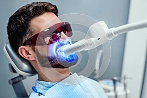 Close up view of man undergoing laser tooth whitening treatment to remove stains and discoloration