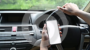 Close up view of man using smart phone while driving car.