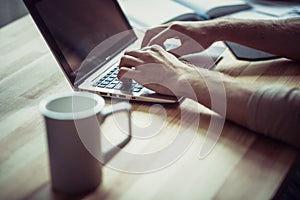 Close up view of mans hands keyboarding on laptop.