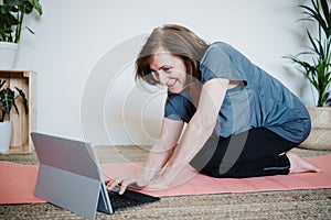 close up view of mature caucasian senior woman practicing yoga pose at home. using laptop for online class with teacher. Healthy