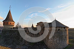 Close up view of medieval Kamianets-Podilskyi Castle. Thick stone walls and tall towers. Colorful vibrant sky during sunset.